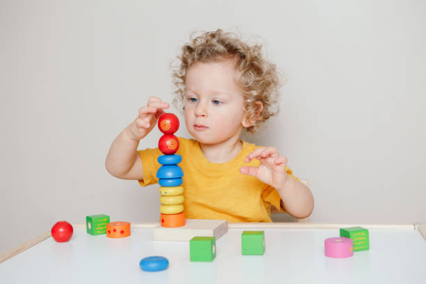 istock Cute baby toddler playing with learning toy pyramid stacking blocks at home or kindergarten. Early age education. Kids hand brain fun development activity for preschoolers. 1299323068