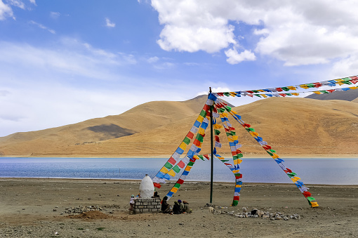 Several local Tibetans are sitting by the lake to rest and enjoying the view of Yamdrok Lake in Tibet, China.
