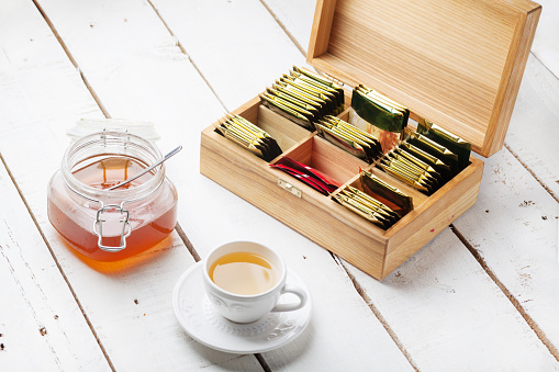 wooden box with tea bag on white table, tea cup, honey