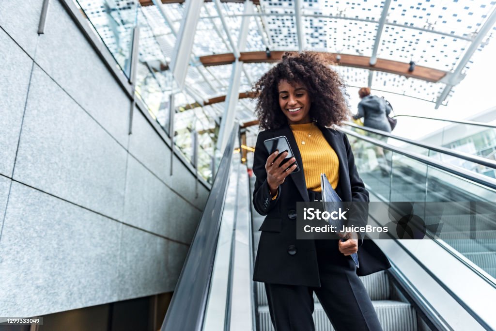 Businesswoman uses phone in public Portrait of young business woman on a escalator Banking Stock Photo