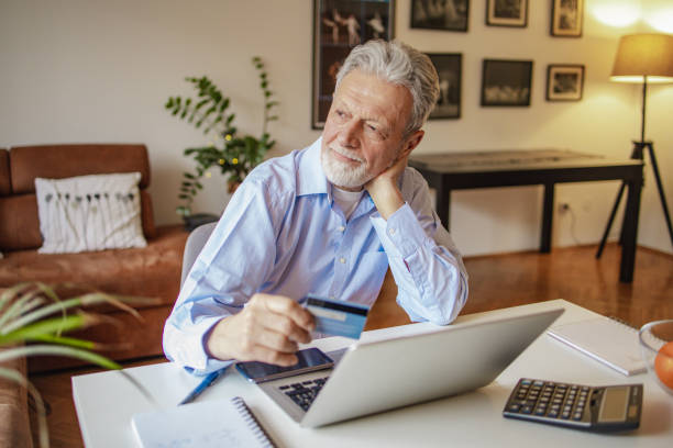istock Senior man using credit card for online shopping at home 1299334177