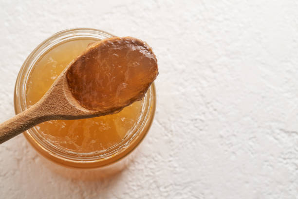 istock Cooled down congealed beef bone broth in a glass jar and on a spoon, on a white background 1299335861