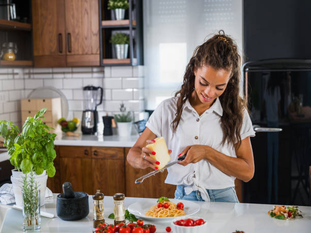 jeune chef râpant le fromage au-dessus des pâtes fraîchement faites maison de tomate et de basilic - grater photos et images de collection