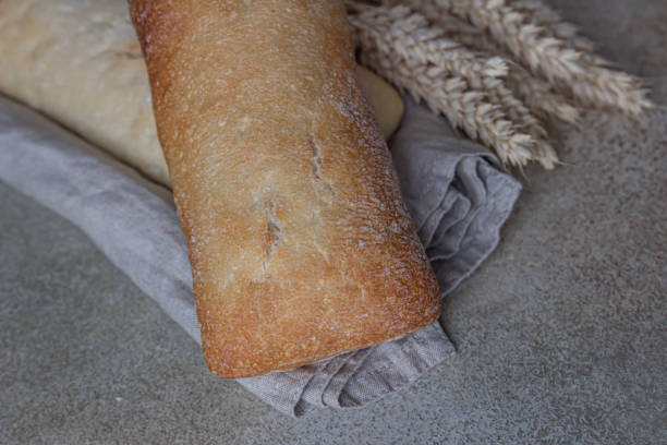 istock Crispy Italian ciabatta bread on linen napkin, stone background. Top view. 1299338114