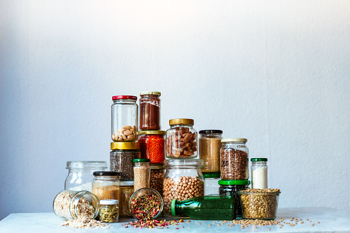a collection of dry foods like chickpeas and lentils all totally whole food plant-based vegan lifestyle. In jars upon a countertop in a stylized European kitchen