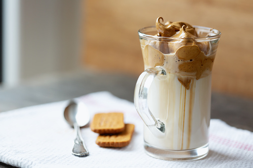 Dalgona coffee in a glass, fluffy  whipped  coffee  cream  on milk, decorated with biscuits