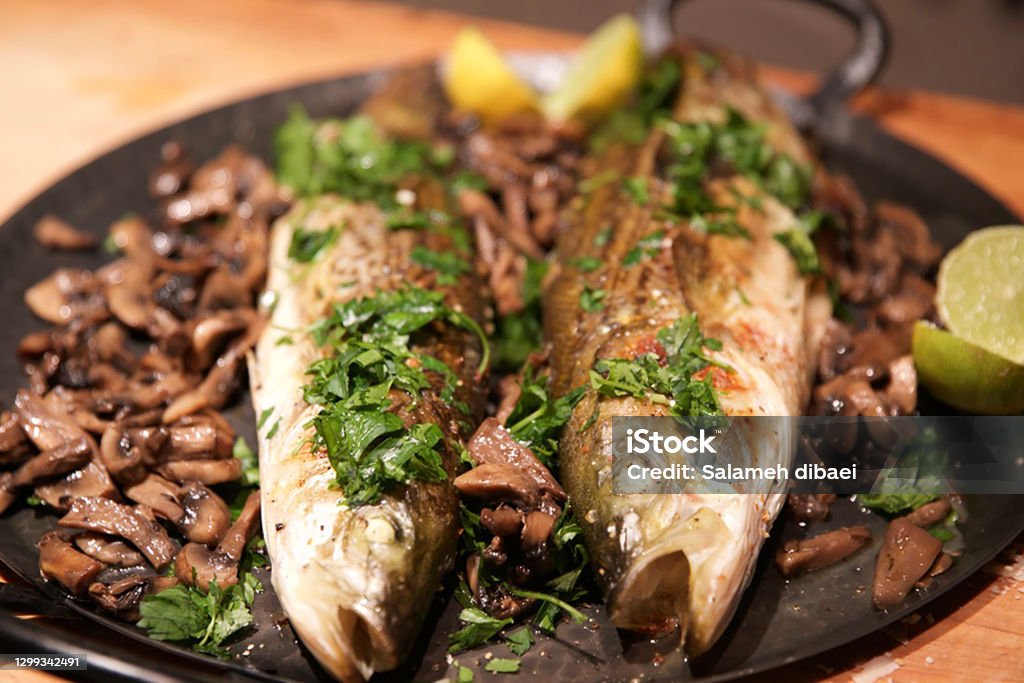 Grilled Chilean Sea bass Grilles Sea bass dinner with mushroom, garlic, pepper parsley and fresh Lemon Sea Bass Stock Photo
