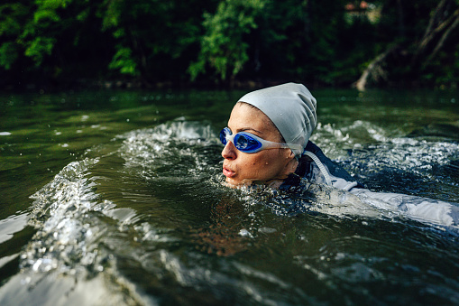 Photo of a young female triathlete swimming in the river, as a part of a triathlon training.