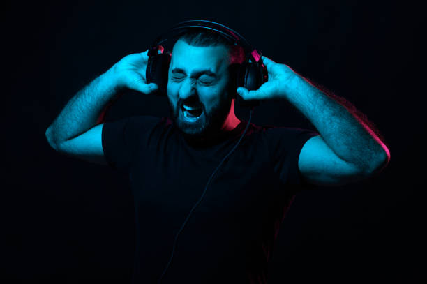 istock Screaming bearded musician dj with headphones on black isolated background 1299343661