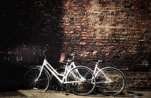 Two white classic bikes parked on a brick wall