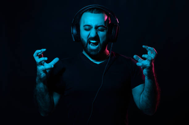 istock Screaming bearded musician dj with headphones on black isolated background 1299344091