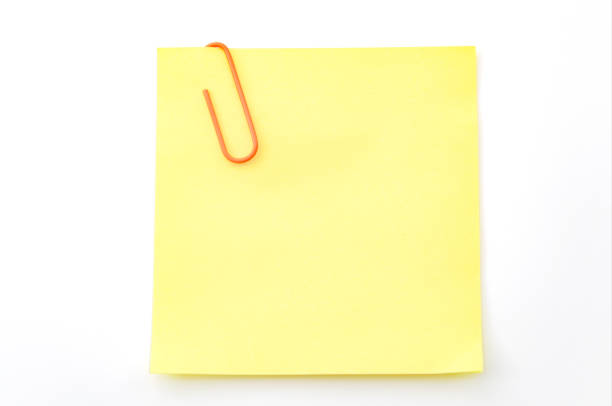 istock Office memo and reminder note concept with blank self adhesive yellow sticky note with paperclip isolated on white background with copy space and clipping path cutout 1299344814