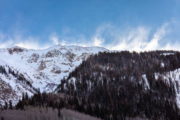 The morning sun illuminates snow blowing over a mountain ridge in the San Juan Mountains of Southeastern Colorado