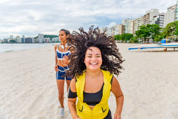 istock Happy young women runs together on the beach 1299351618