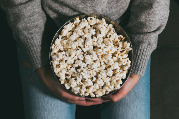 istock Close-up of hands with popcorn bowl 1299353378