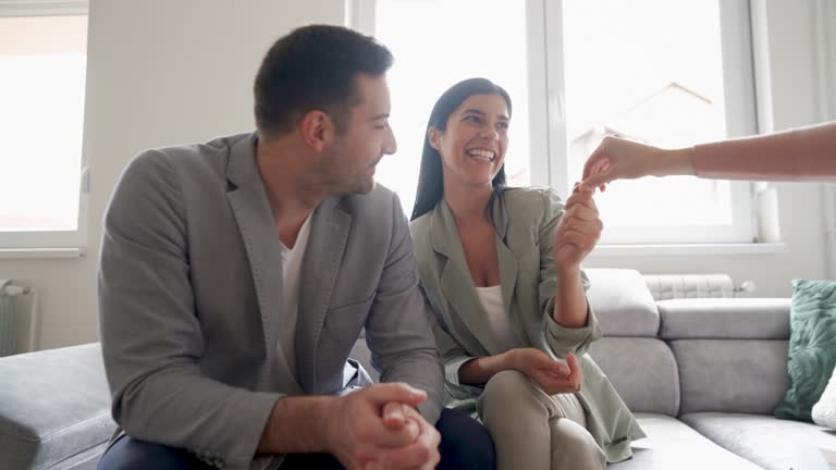 Happy young couple signing documents and taking the key to their new house