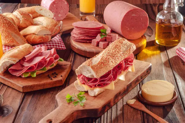 Mortadella sandwich with butter, bread and spices on wood background