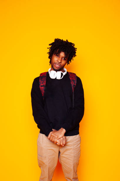 istock young handsome african american guy student posing cheerful and gesturing on yellow background, lifestyle people concept 1299357750