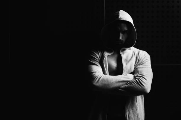 istock Model Flexing Muscles In Sweatshirt Against the Wall 1299359035