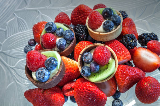 istock Fruit tarts on top of mixed berry background 1299360733