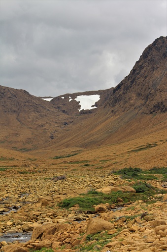 Dark summer clouds loom over an expanse of the stark, rocky beauty of the Tablelands ophiolite, Gros Morne National Park, Canada, Newfoundland.  An ophiolite is a section of ancient ocean floor and upper mantle, long ago thrust upon the continental crust.