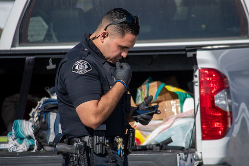 Ventura, California, United States -  August 7, 2020: An officer from the City of Ventura Police Department conduct a search of a suspect's vehicle at Ventura Harbor.  Two firearms were seized and two suspects arrested.  The incident happened at Ventura Harbor Cove Beach, in the parking lot.