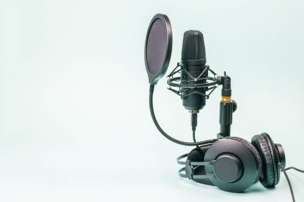 istock Black headphones and microphone with wires on a light blue background. 1299372354