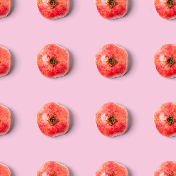 istock Seamless pattern with red pomegranate fruit on pink background. Minimal flat lay concept. 1299376932