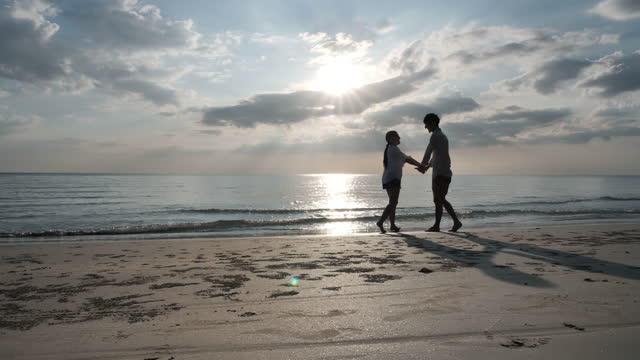 Young couple in love holding hands Spinning around on the beach