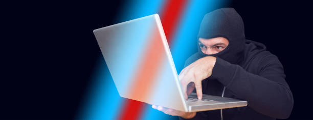 istock Hacker using laptop to steal identity at desk 1299380198