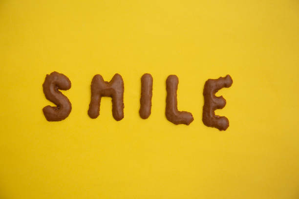 istock Word SMILE arranged from homemade chocolate cookie alphabet on yellow table 1299380269