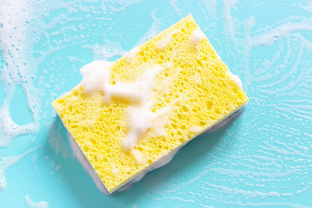 Yellow sponge with foam on a blue background close-up. Yellow sponge with foam on a blue background close up. cleaning sponge photos stock pictures, royalty-free photos & images