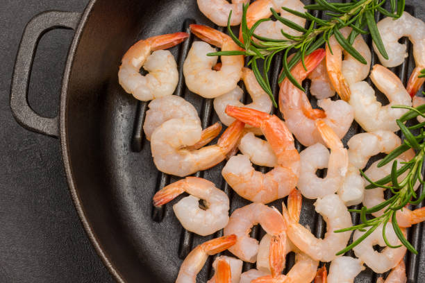 istock Shrimp with rosemary sprigs in frying pan. 1299389278