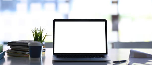 istock Front view of modern workplace with mock up laptop computer, book, plant and coffee cup. 1299389408