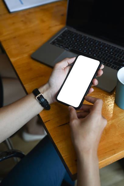 istock Close up view of female using smart phone while sitting at her workplace. Blank screen for advertise text. 1299389967