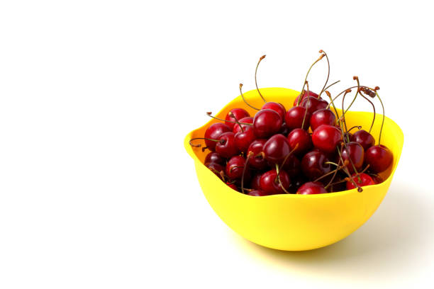 istock Ripe sweet cherries in a yellow cup close-up on white. 1299398271