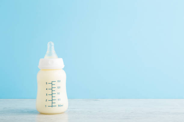 Bottle of white milk on wooden table at light blue wall background. Baby feeding concept. Pastel color. Closeup. Empty place for text. Front view. Bottle of white milk on wooden table at light blue wall background. Baby feeding concept. Pastel color. Closeup. Empty place for text. Front view. formula stock pictures, royalty-free photos & images