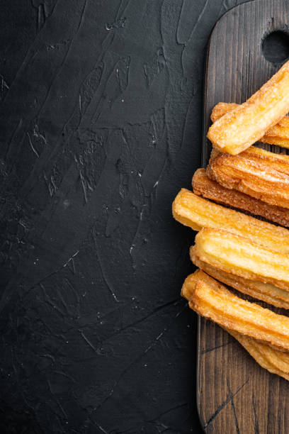 istock Churros with caramel Traditional Spanish cusine, on black background, top view flat lay with space for text, copyspace 1299402629