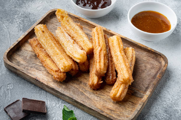 istock Typical Spanish snack  churros, fried-dough pastry served  usually with chocolate caramel hot sauce, on gray background 1299402717