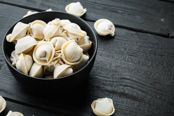 istock Frozen tortellini in black bowl, on black wooden table background , with copyspace  and space for text 1299402840