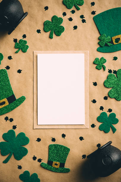 istock Happy Saint Patrick's day concept. Vertical banner design with greeting card mockup, Irish elf hats, pots of gold, shamrock clover leaves on kraft paper background. Vintage, retro style 1299403389