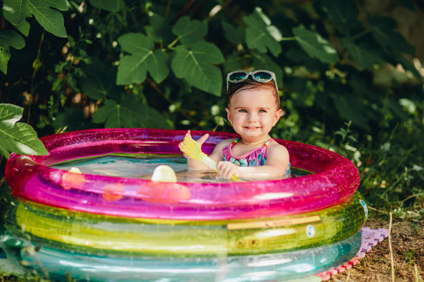 istock Cheerful baby enjoying her day in sumer in her pool holding plastic scoop 1299403609