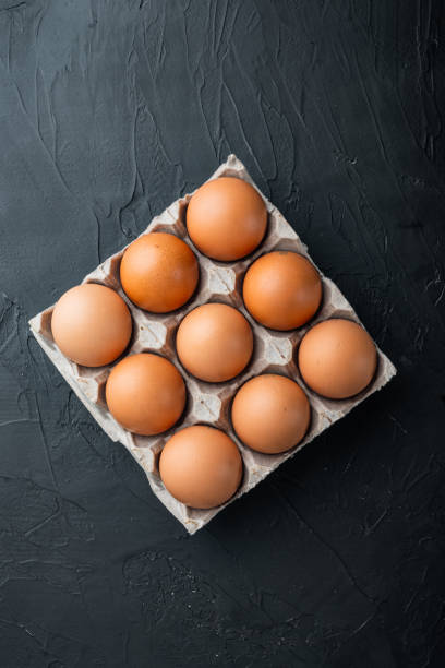 istock Fresh eggs on paper egg box, on black background, top view flat lay 1299404588