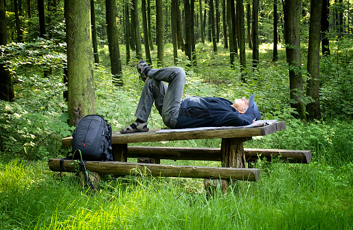 Senior man taking a rest on a wooden table in the forest