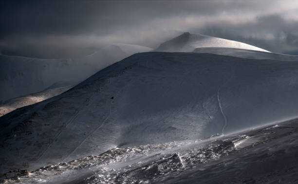 istock Snow covered mountain slope in last evening sunlight. Magnificent windy dusk on tops above picturesque alpine ski resort, Dragobrat, Ukraine, Carpathian Mountains. 1299405895