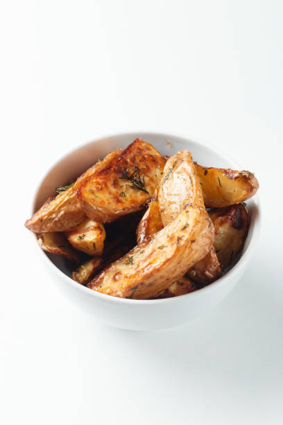 istock Bowl with tasty potato wedges on white isolated background 1299405938