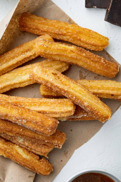 istock Tasty churros with chocolate caramel sauce, on white background, top view flat lay 1299406952