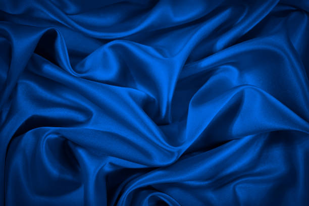 istock Deep blue silk satin fabric. Elegant abstract background. Liquid wave effect or silk with soft wavy folds. 1299406991