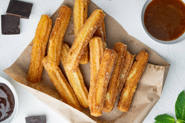 istock Churros with sugar and chocolate sauce, on white background, top view flat lay 1299408165