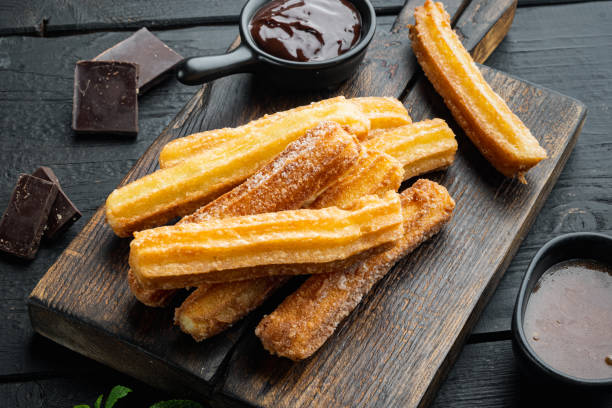 istock Churros with sugar and chocolate sauce, on black wooden table background 1299408940